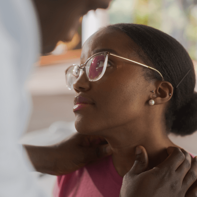 Physician inspects neck muscles of a female patient during a check-up visit to a clinic.